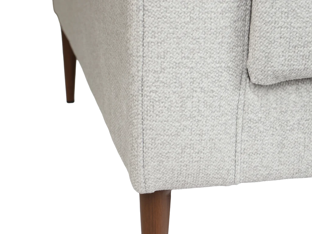 Detalle de la pata de un sofá de tela gris claro con patas de madera oscura.