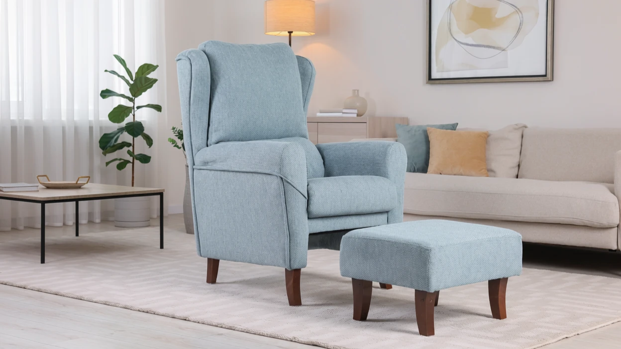 Silla de reclinación azul claro con reposapiés en una sala de estar moderna con sofá beige