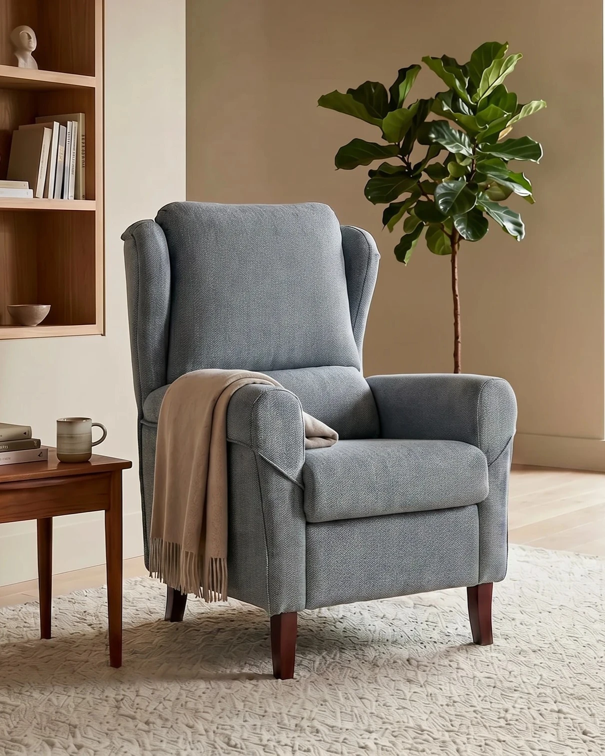 Silla de lectura gris con respaldo alto en una habitación minimalista con alfombra beige y planta